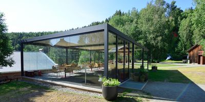 Glassinnrammet pergola i grønne omgivelser